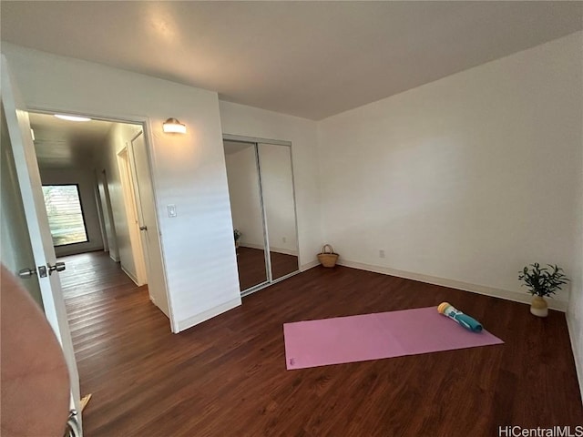 unfurnished bedroom with dark hardwood / wood-style flooring and a closet