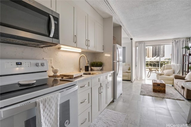 kitchen with white cabinets, sink, stainless steel appliances, and a textured ceiling