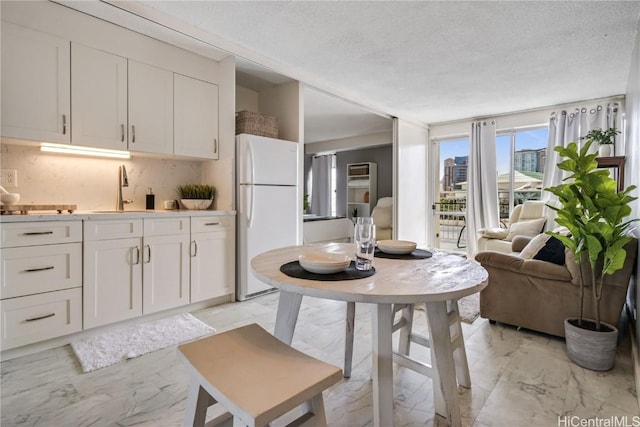 kitchen with backsplash, sink, a textured ceiling, white cabinets, and white refrigerator