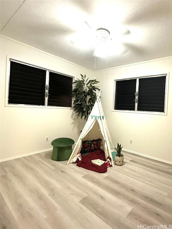 rec room with a textured ceiling, baseboards, and wood finished floors