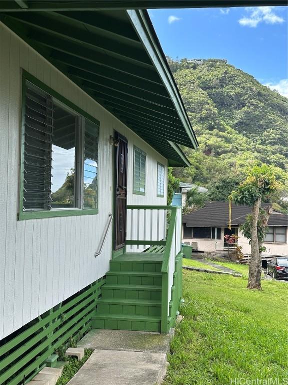 view of side of property featuring a mountain view and a lawn