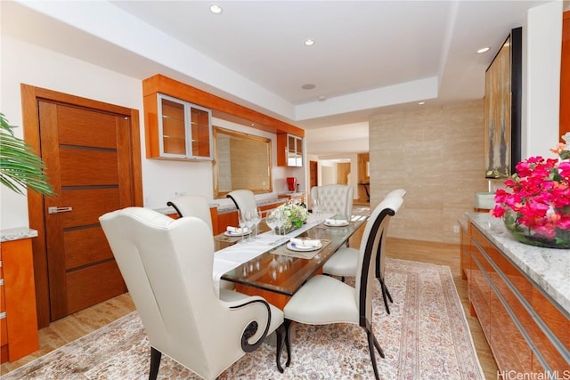 dining area featuring a raised ceiling and light wood-type flooring