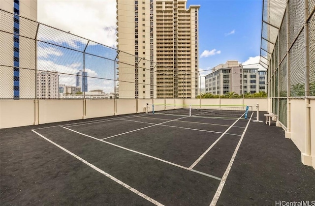 view of sport court with a city view and fence