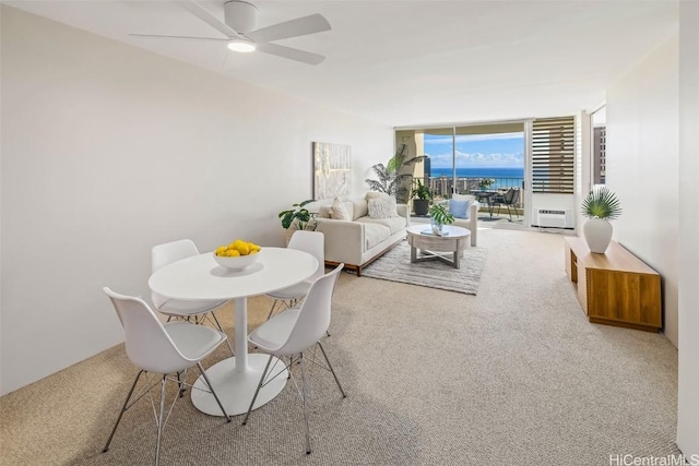 carpeted dining room with expansive windows and ceiling fan