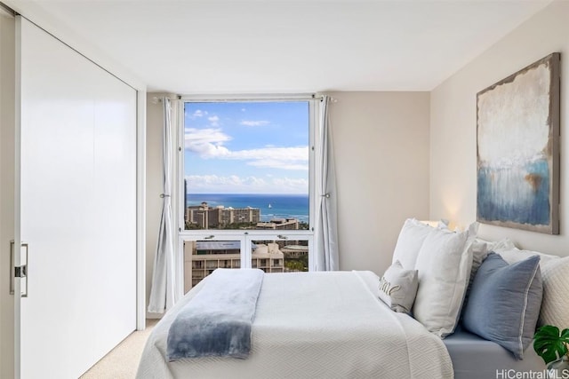 carpeted bedroom with floor to ceiling windows and a water view