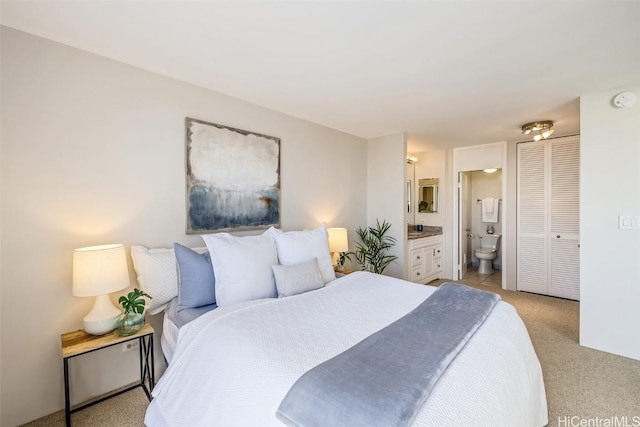 bedroom with ensuite bath and light carpet