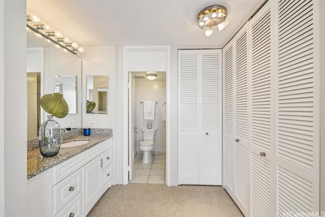 bathroom featuring vanity, tile patterned floors, toilet, and a closet