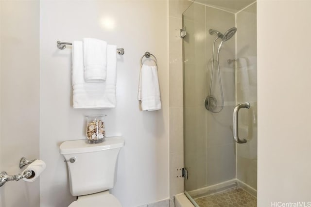 bathroom with a shower with shower door and toilet