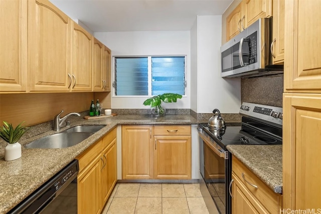 kitchen featuring light tile patterned floors, dark stone countertops, stainless steel appliances, and a sink