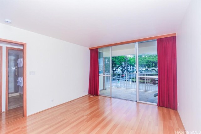 spare room featuring expansive windows and hardwood / wood-style flooring