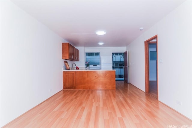 kitchen with kitchen peninsula, light wood-type flooring, and sink