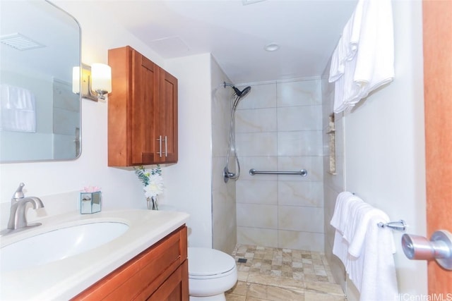 bathroom featuring vanity, toilet, and tiled shower