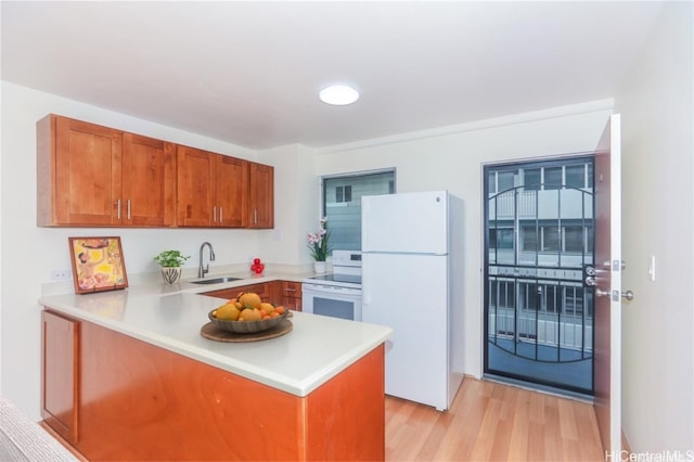 kitchen featuring kitchen peninsula, white appliances, light hardwood / wood-style flooring, and sink