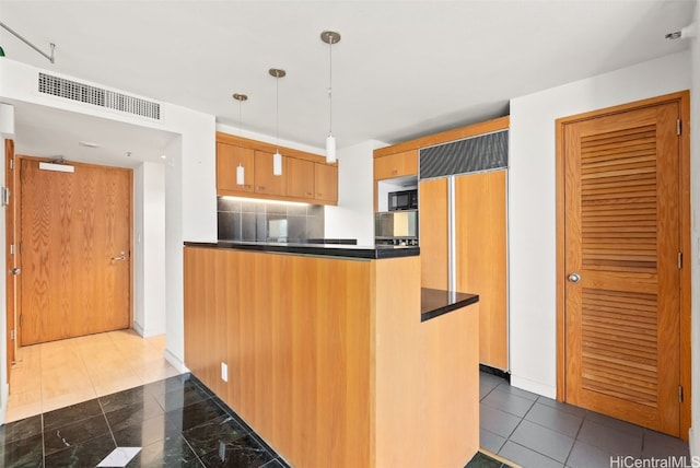 kitchen with kitchen peninsula, paneled built in refrigerator, pendant lighting, decorative backsplash, and light brown cabinetry