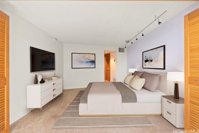 bedroom featuring light colored carpet and track lighting