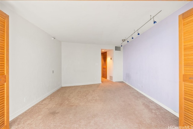 spare room with light colored carpet and track lighting