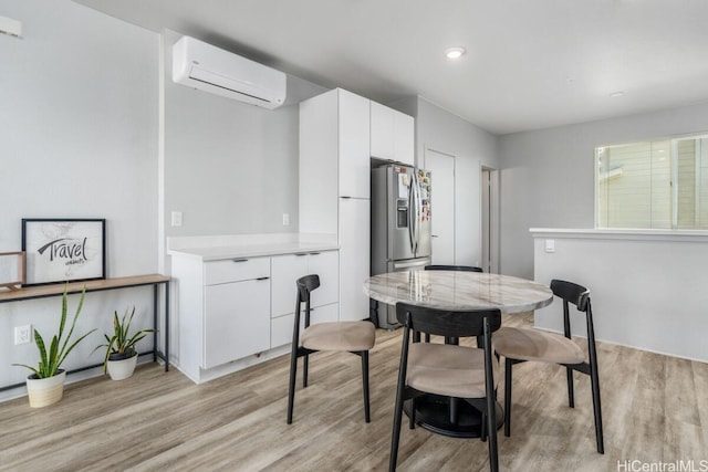 dining room with a wall mounted air conditioner and light hardwood / wood-style floors