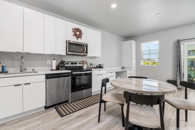 kitchen featuring white cabinetry, sink, appliances with stainless steel finishes, and light hardwood / wood-style flooring