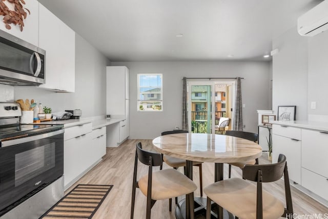 kitchen with white cabinetry, stainless steel appliances, and a wall mounted air conditioner