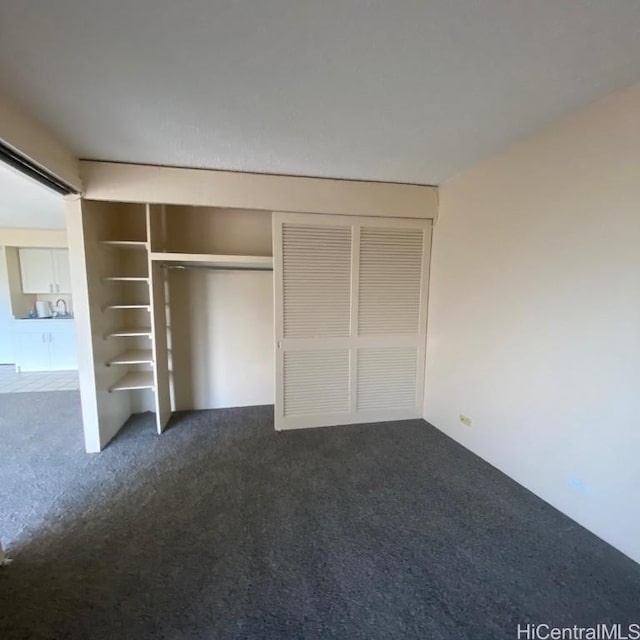 unfurnished bedroom with dark colored carpet and a closet