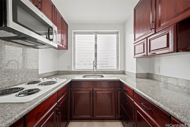 kitchen with decorative backsplash, light stone counters, white stovetop, and sink