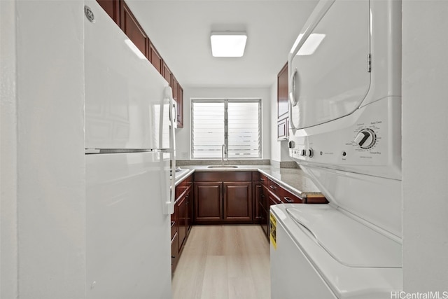 washroom featuring sink, light wood-type flooring, and stacked washer and dryer