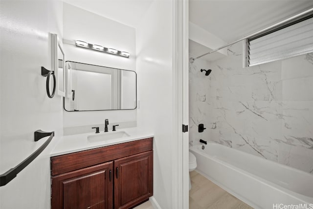 full bathroom featuring vanity, tiled shower / bath combo, hardwood / wood-style flooring, and toilet