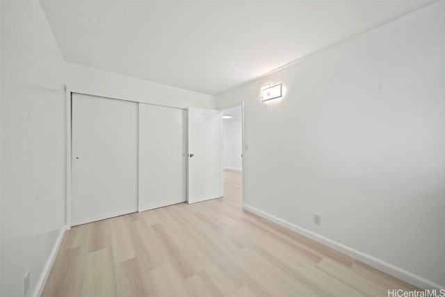 unfurnished bedroom with light wood-type flooring and a closet