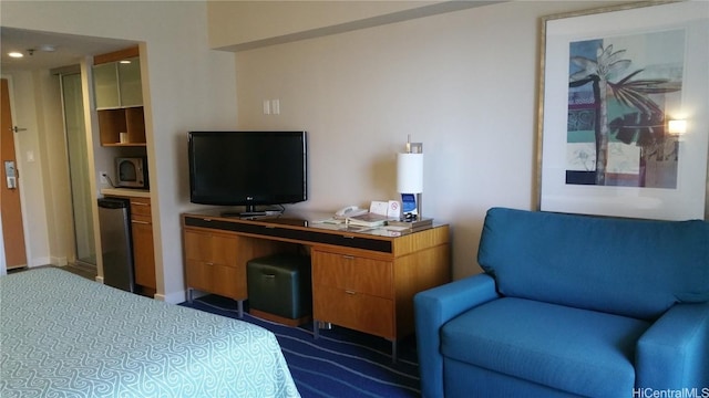 bedroom with dark colored carpet and fridge