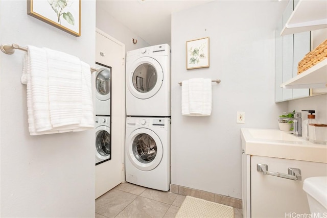 laundry area with light tile patterned floors, stacked washer / drying machine, and sink