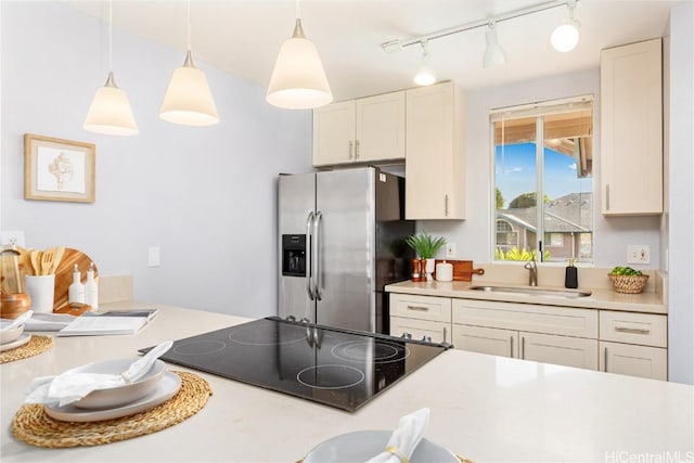 kitchen with sink, hanging light fixtures, stainless steel refrigerator with ice dispenser, black electric cooktop, and white cabinets