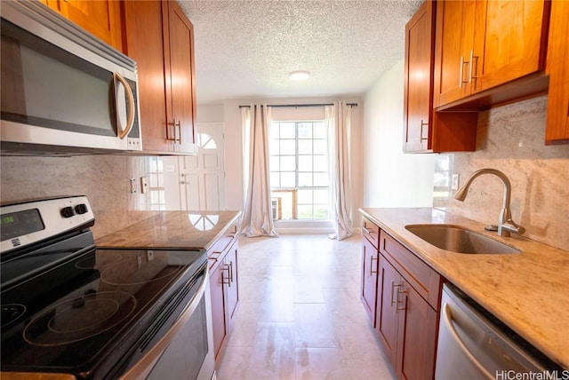 kitchen featuring backsplash, sink, appliances with stainless steel finishes, and a textured ceiling