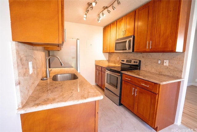 kitchen with backsplash, light stone countertops, sink, and appliances with stainless steel finishes