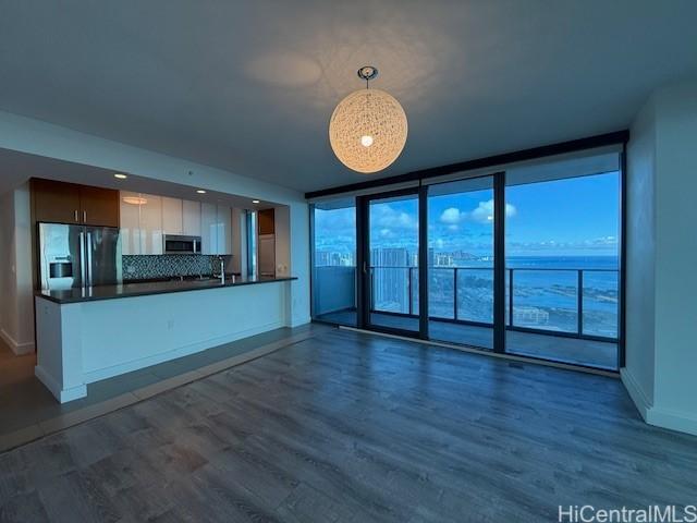 kitchen featuring dark wood-type flooring, tasteful backsplash, decorative light fixtures, white cabinetry, and fridge with ice dispenser