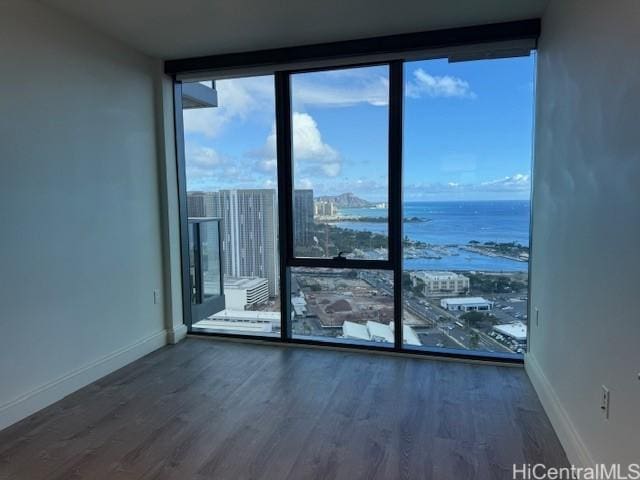 unfurnished room featuring a water view, a wall of windows, and dark hardwood / wood-style floors