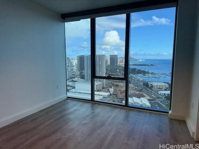 empty room with a water view, dark wood-type flooring, expansive windows, and a healthy amount of sunlight