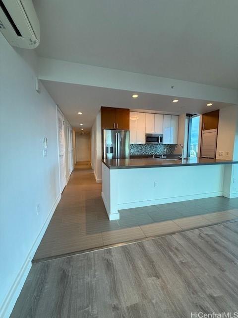 kitchen featuring an AC wall unit, light hardwood / wood-style flooring, white cabinets, and stainless steel appliances