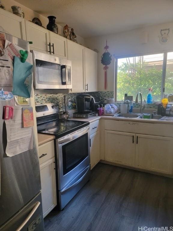 kitchen with appliances with stainless steel finishes, tasteful backsplash, dark wood-type flooring, sink, and white cabinets