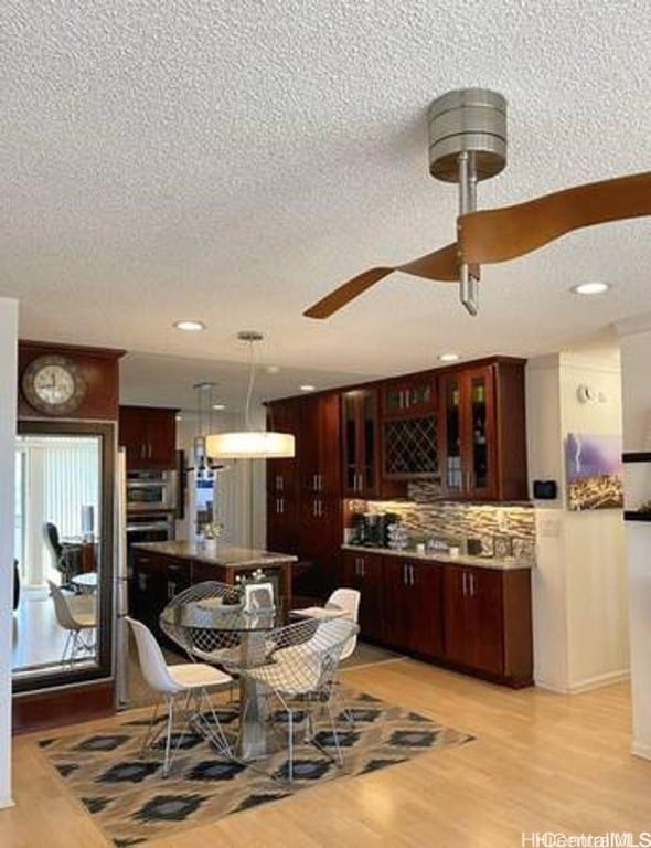 dining space with ceiling fan, a textured ceiling, and light hardwood / wood-style flooring