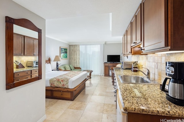 kitchen featuring light stone countertops, sink, tasteful backsplash, crown molding, and light tile patterned floors