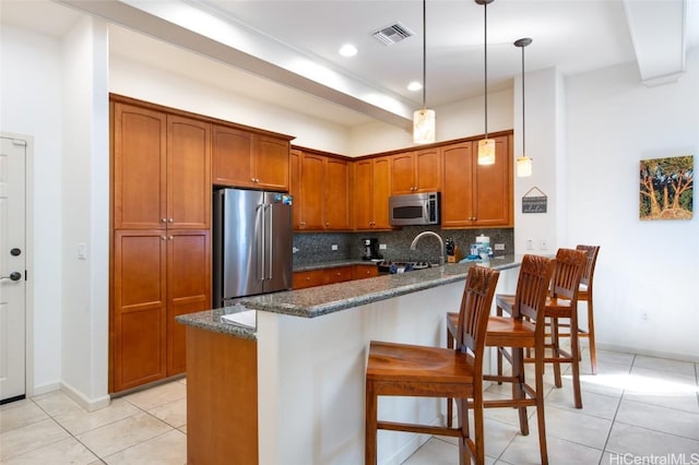 68-1125 N Kaniku Dr Unit 102, Kamuela, HI 96743 - kitchen with kitchen peninsula, hanging light fixtures, appliances with stainless steel finishes, and dark stone counters
