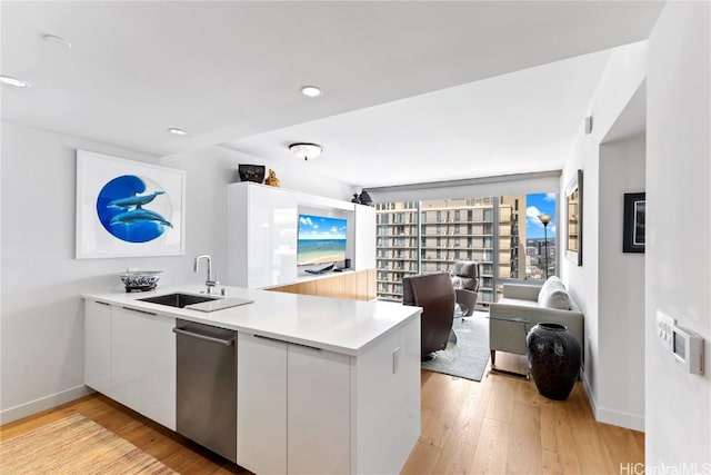 kitchen with kitchen peninsula, light hardwood / wood-style floors, white cabinetry, and sink