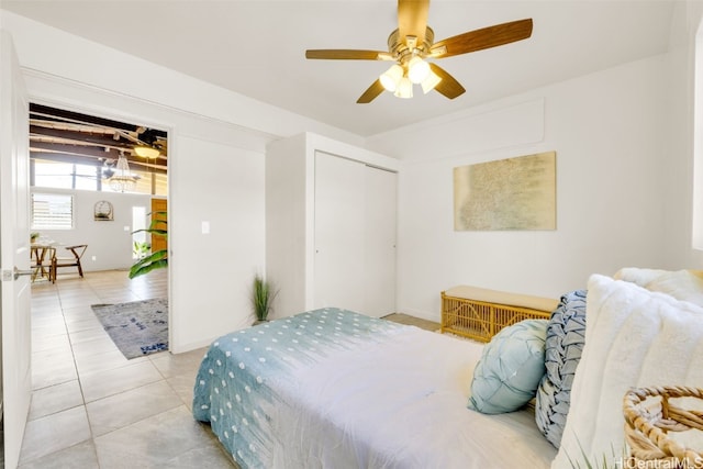 tiled bedroom with ceiling fan and a closet