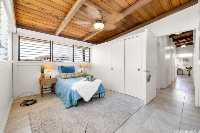 bedroom featuring ceiling fan, lofted ceiling with beams, wooden ceiling, and light tile patterned floors