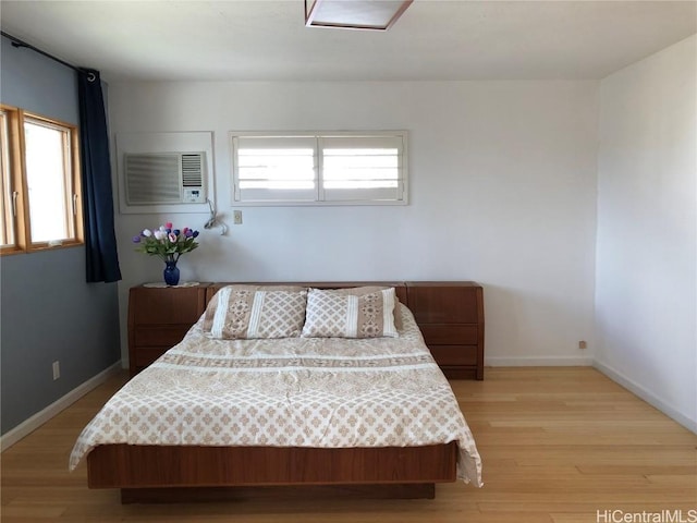 bedroom with a wall mounted AC and light hardwood / wood-style floors