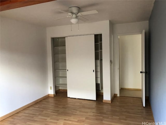 unfurnished bedroom with ceiling fan, a closet, and hardwood / wood-style flooring