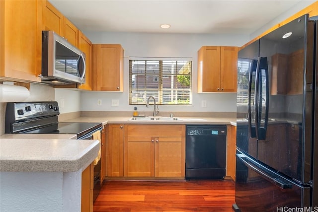 kitchen with sink, dark wood-type flooring, and black appliances