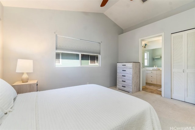 bedroom with ensuite bath, ceiling fan, light colored carpet, vaulted ceiling, and a closet