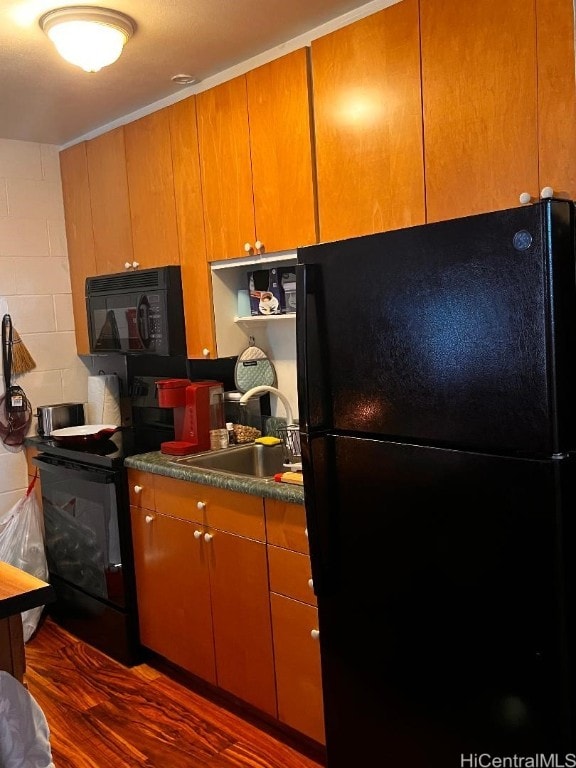 kitchen featuring black appliances, dark hardwood / wood-style floors, and sink