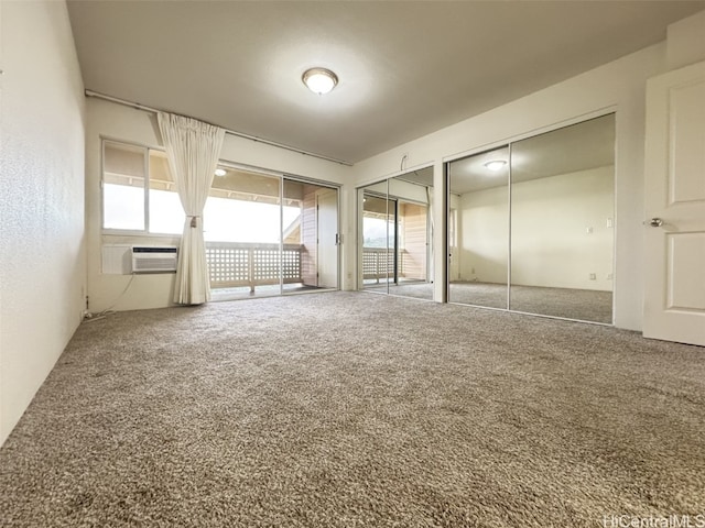 unfurnished bedroom with carpet flooring, a wall mounted air conditioner, and two closets